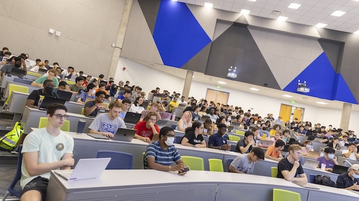 Students listen intently during a computer science class at Georgia Tech in a large modern auditorium-style classroom