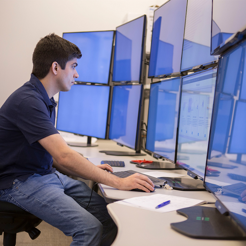 Man sitting at desk with wrap around monitors