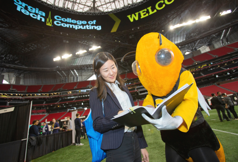 student and buzz reviewing resume at career fair