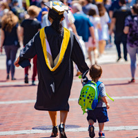 Woman in a Tech robe walking with a child