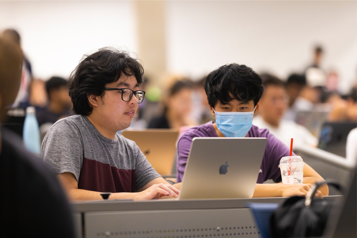 Two students look at a laptop