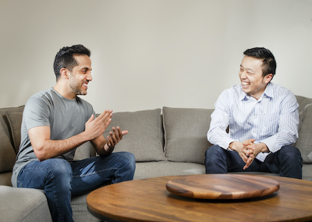 Candid photo of SnapCommerce co-founders Hussein Fazal (left) and Henry Shi chatting and laughing on a couch.