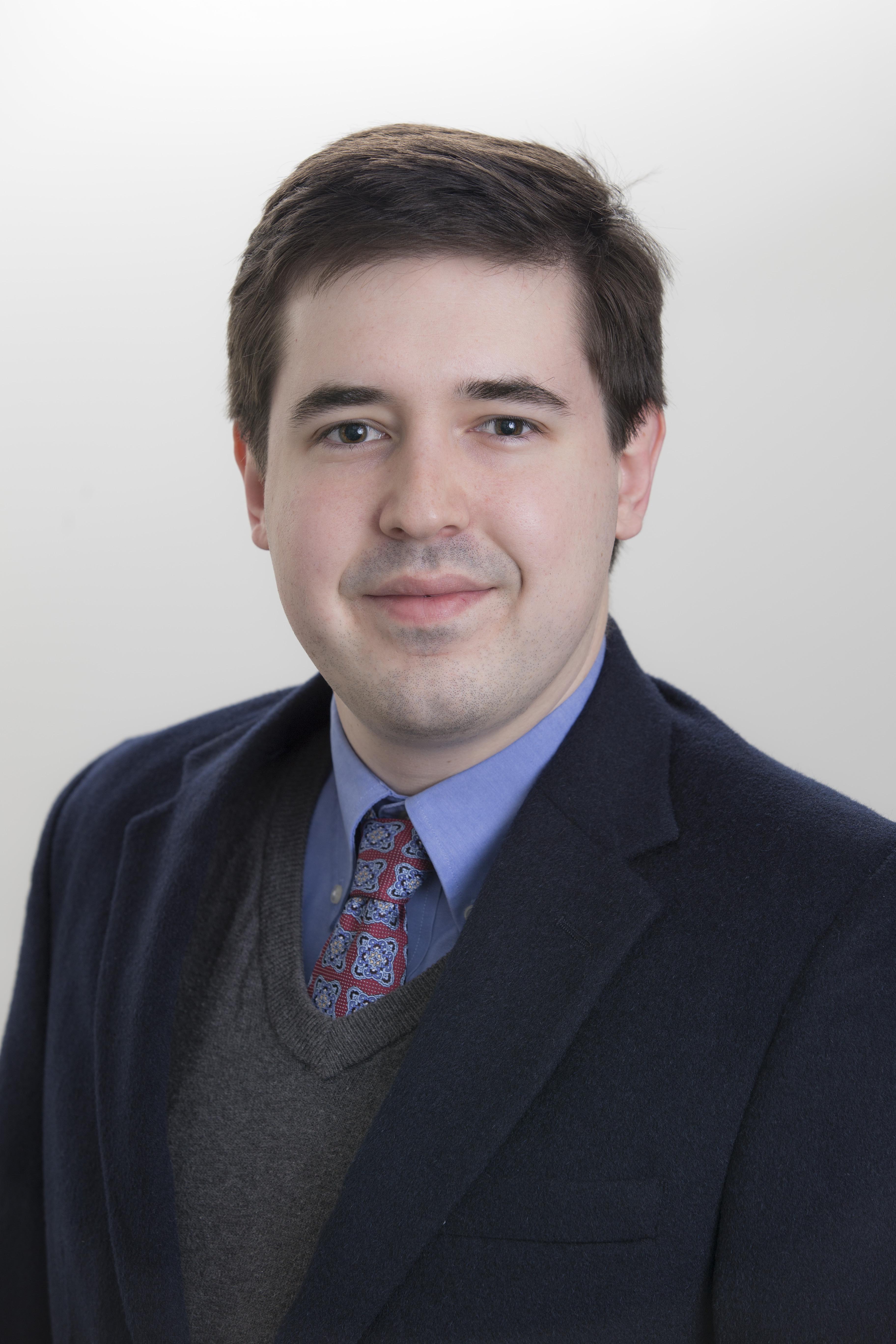 man with brown hair wearing blue suit jacket and grey vest