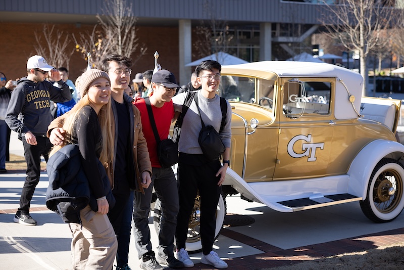 OMSCS graduates pose with Georgia Tech's Ramblin' Wreck