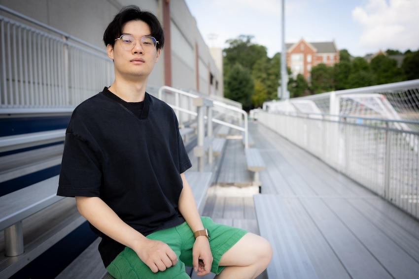 Male student sitting on steel bleachers