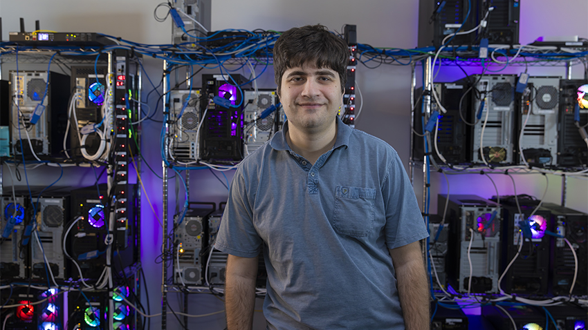 Daniel Genkin standing in front of a row of computer servers in his Georgia Tech laboratory