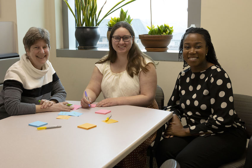 3 women sitting at table looking at camera