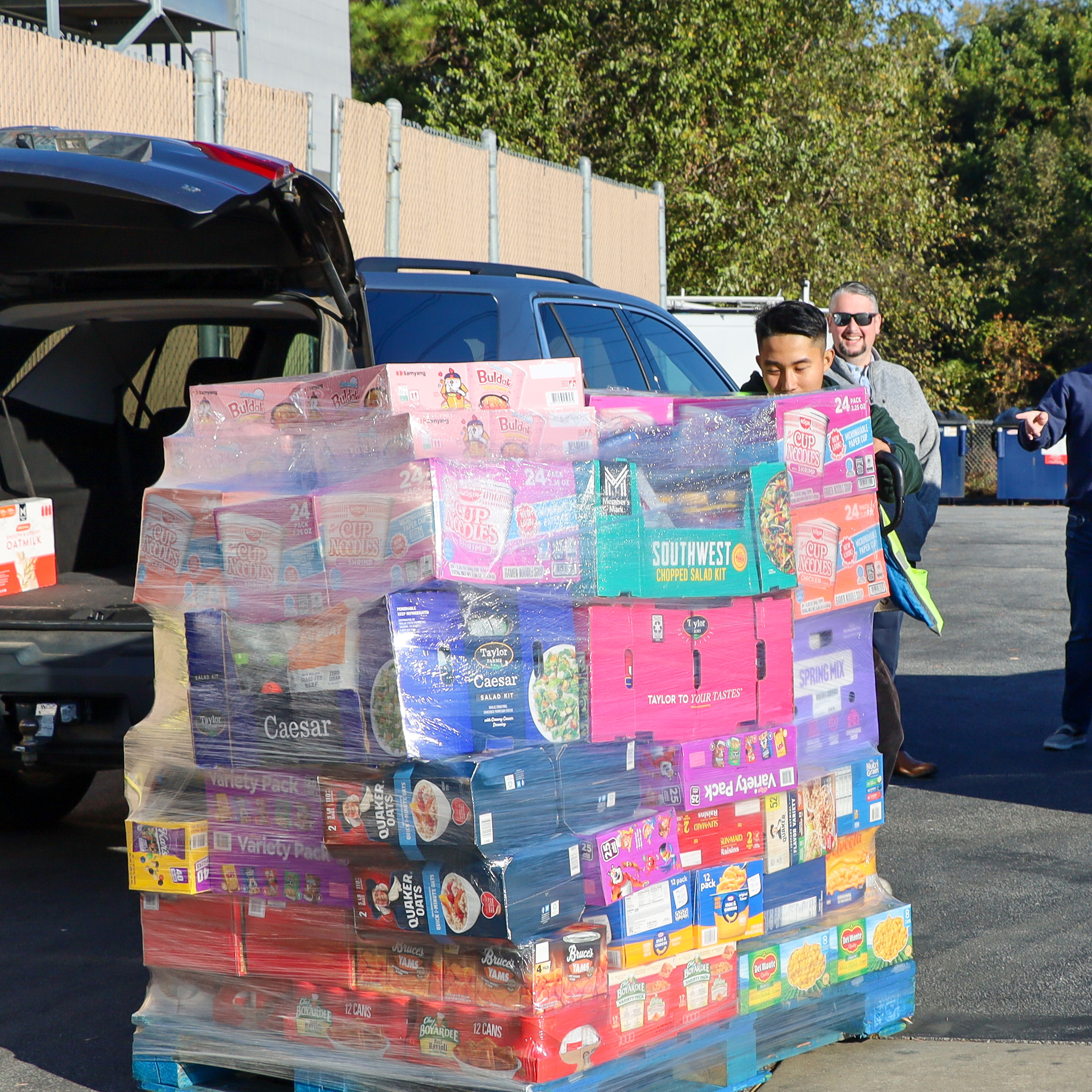 2.	A Sam's employee carts out the food order for the SCP food drive. The pallet of food is tall and wide. There is a diverse mix of food stuffs included in the pallet, such as oatmeal, canned vegetables, cereal, and more.