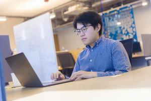 Man sitting at desk looking at laptop.