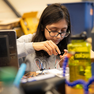 A student wiring a project together.