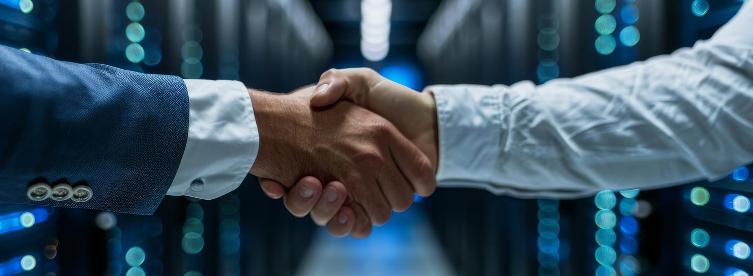 Two people shaking hands in a computer server room.