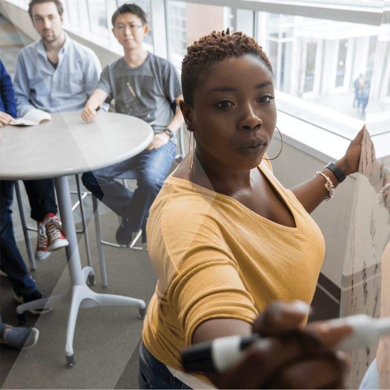 Professor writing on the whiteboard and students watching in the background