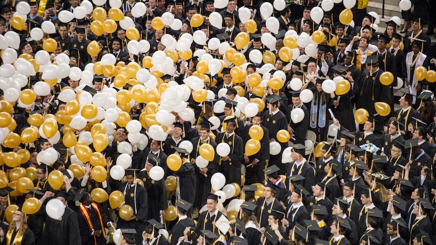 Georgia Tech graduates with gold and white balloons falling.