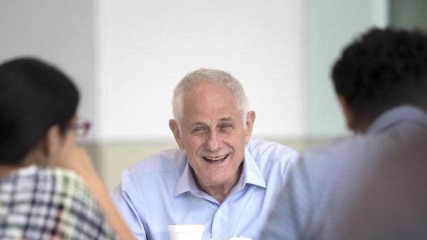 Zvi Galil smiling and facing camera between two people facing him