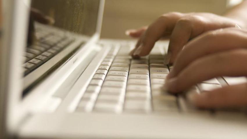 closeup image of hands typing on a laptop computer keyboard.