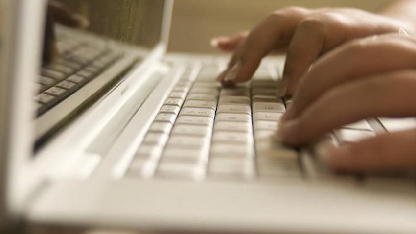 close-up stock photo of fingers on a laptop keyboard