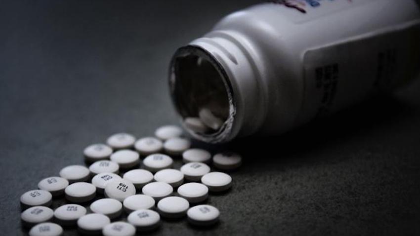 stock photo of white pills spilled out of open prescription bottle