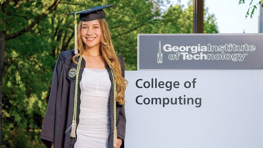 GT Computing alumna Sabrina Seibel in cap and gown next to College of Computing building sign