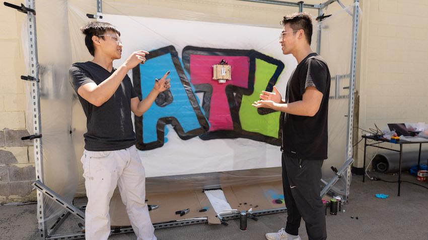 Gerry Chen and Michael Qian with a finished artwork painted by the GTGraffiti robot.