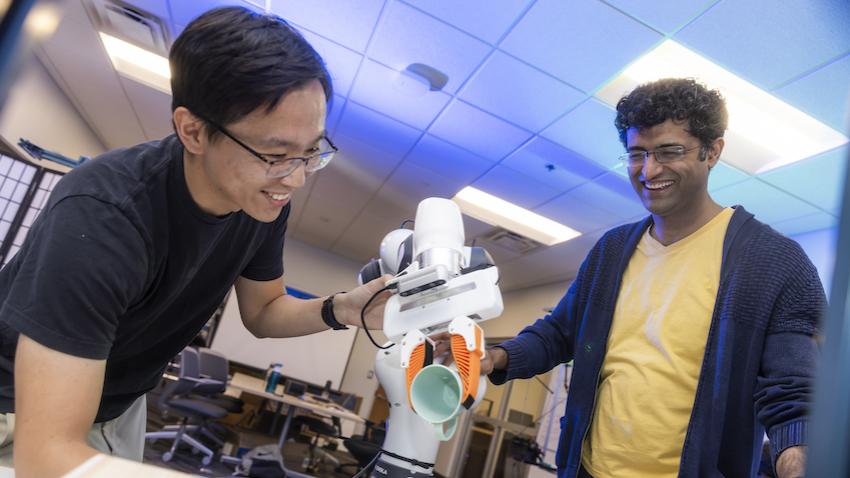 Two men working with robot