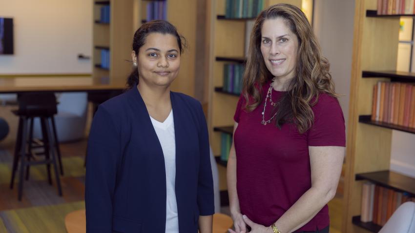 Two women standing in front of a book case