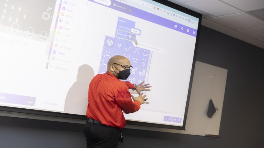 Constellations Fellow, Sababu Barashango points to a screen showing CEP coaches and a coding demonstration.