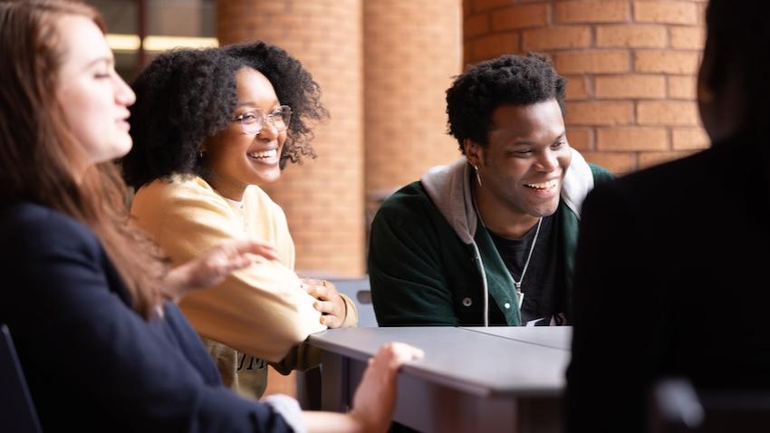Three students sitting at a table laughing