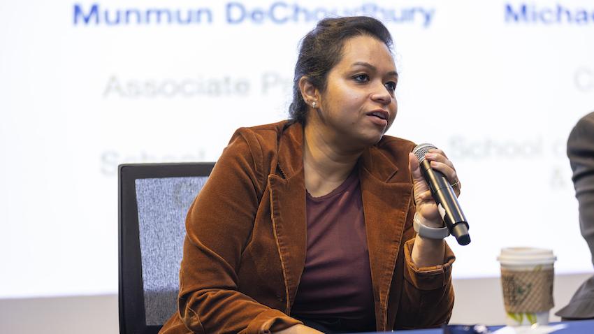 Woman sits in chair holding microphone