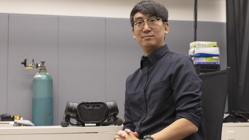 Man sits in chair next to robot