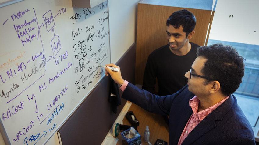 Two faculty members working together on a whiteboard.