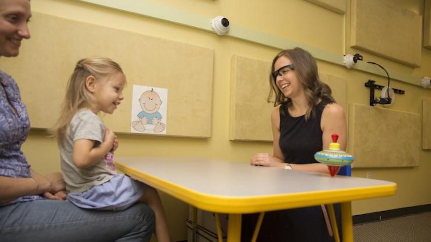A small child plays with toys at a table with her mother and a researcher in Georgia Tech's Child Study Lab.
