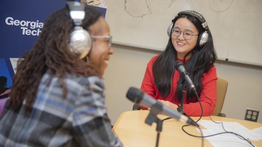 Assistant Professor Diyi Yang speaks with Ayanna Howard on a podcast episode wearing headphones.