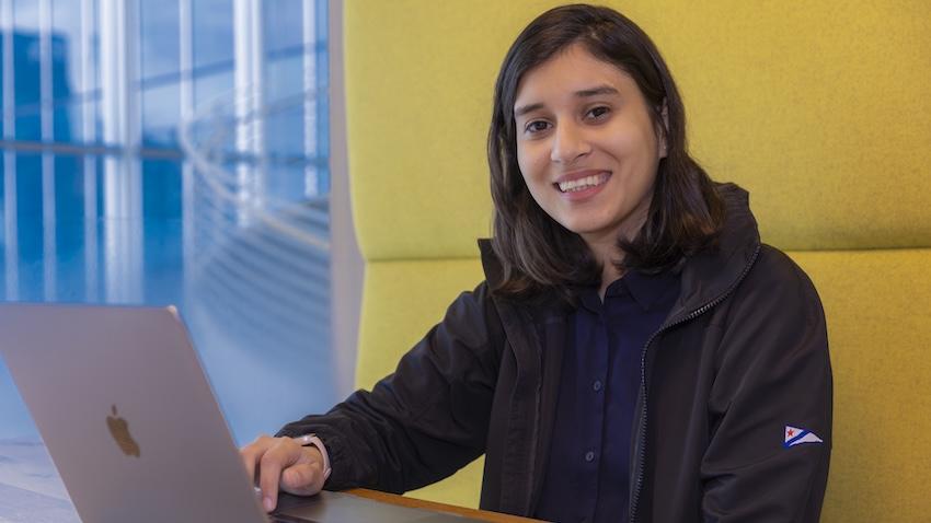 Umme Ammar sits in a booth with laptop in front of her