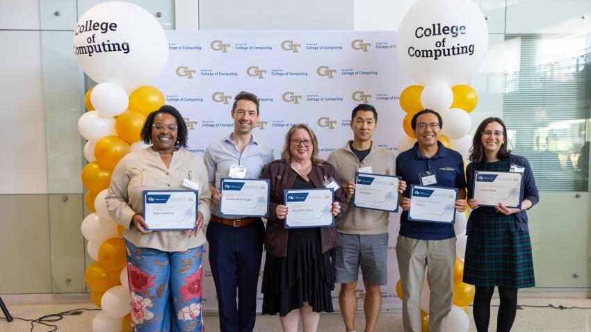 A group photo of people standing in front of a banner holding up certificates