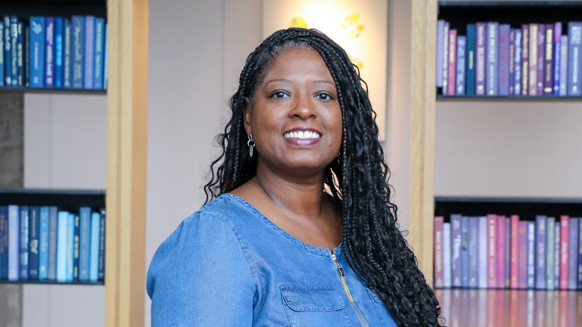 A smiling woman with long hair wearing a blue blouse