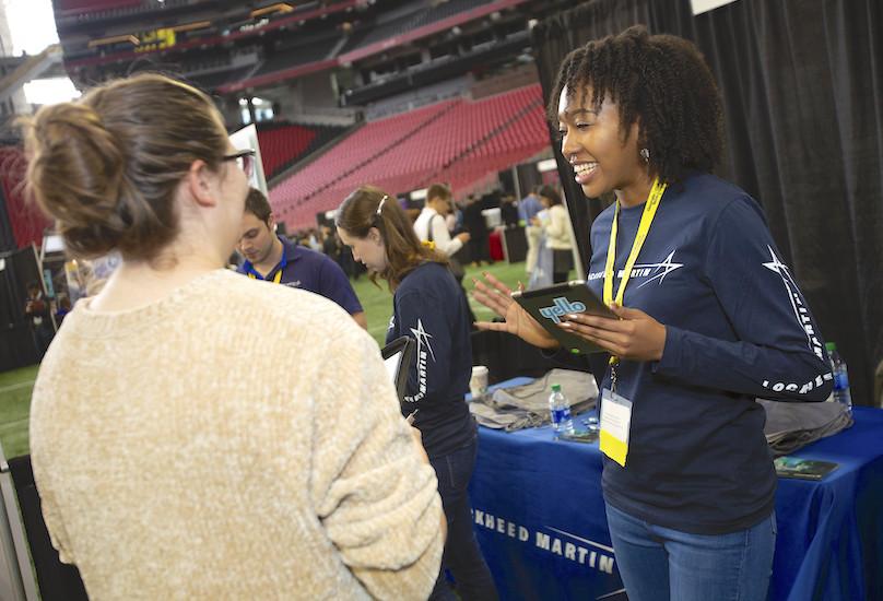 A representative from Lockheed Martin speaking with a GT Computing student during career fair at Mercedes Benz Stadium