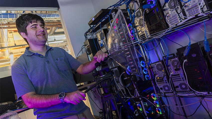 Daniel Genkin, associate professor and Sloan Research Fellow, standing in front of a row of computer servers in his Georgia Tech security lab.
