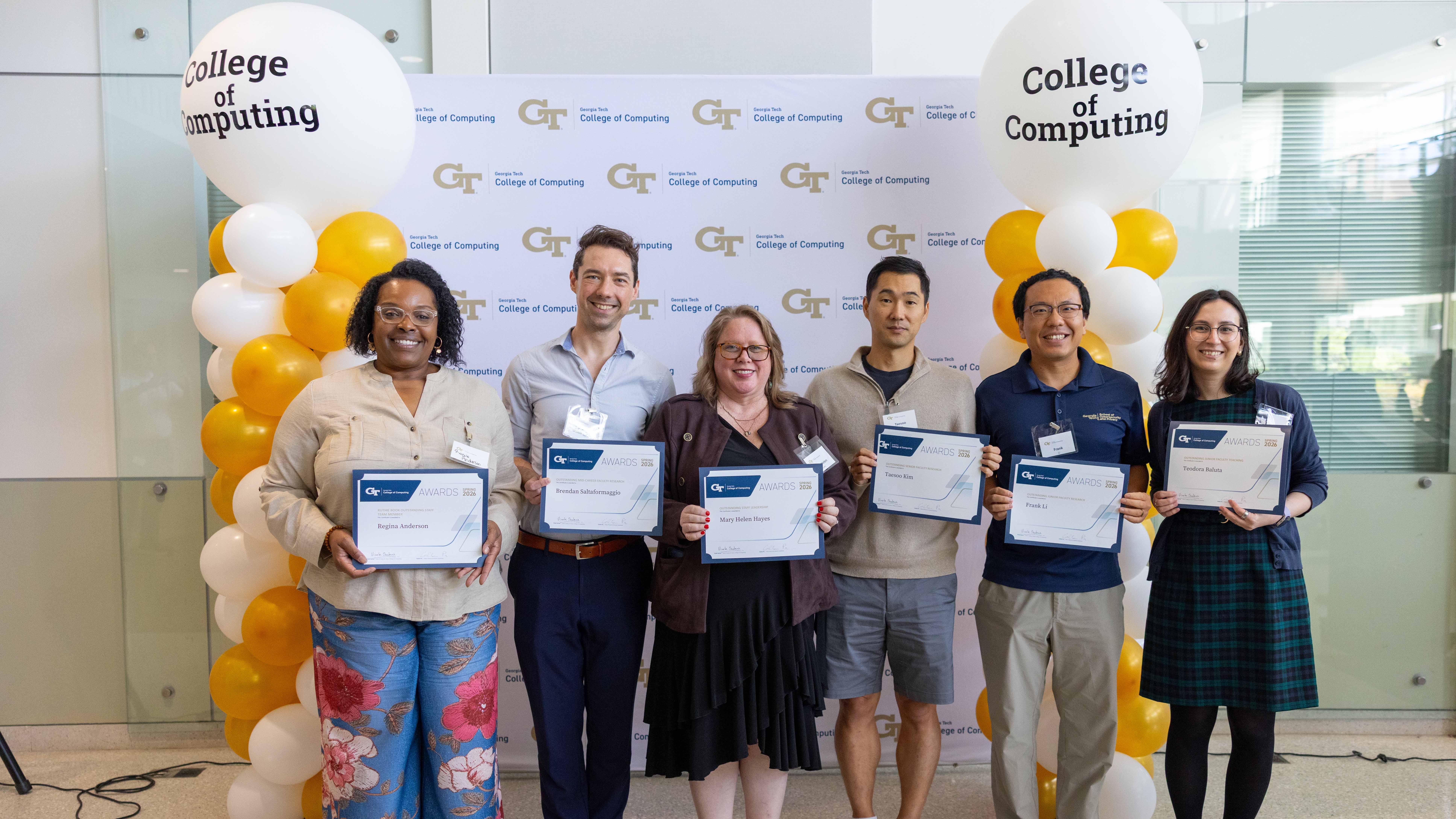 A group photo of people standing in front of a banner holding up certificates