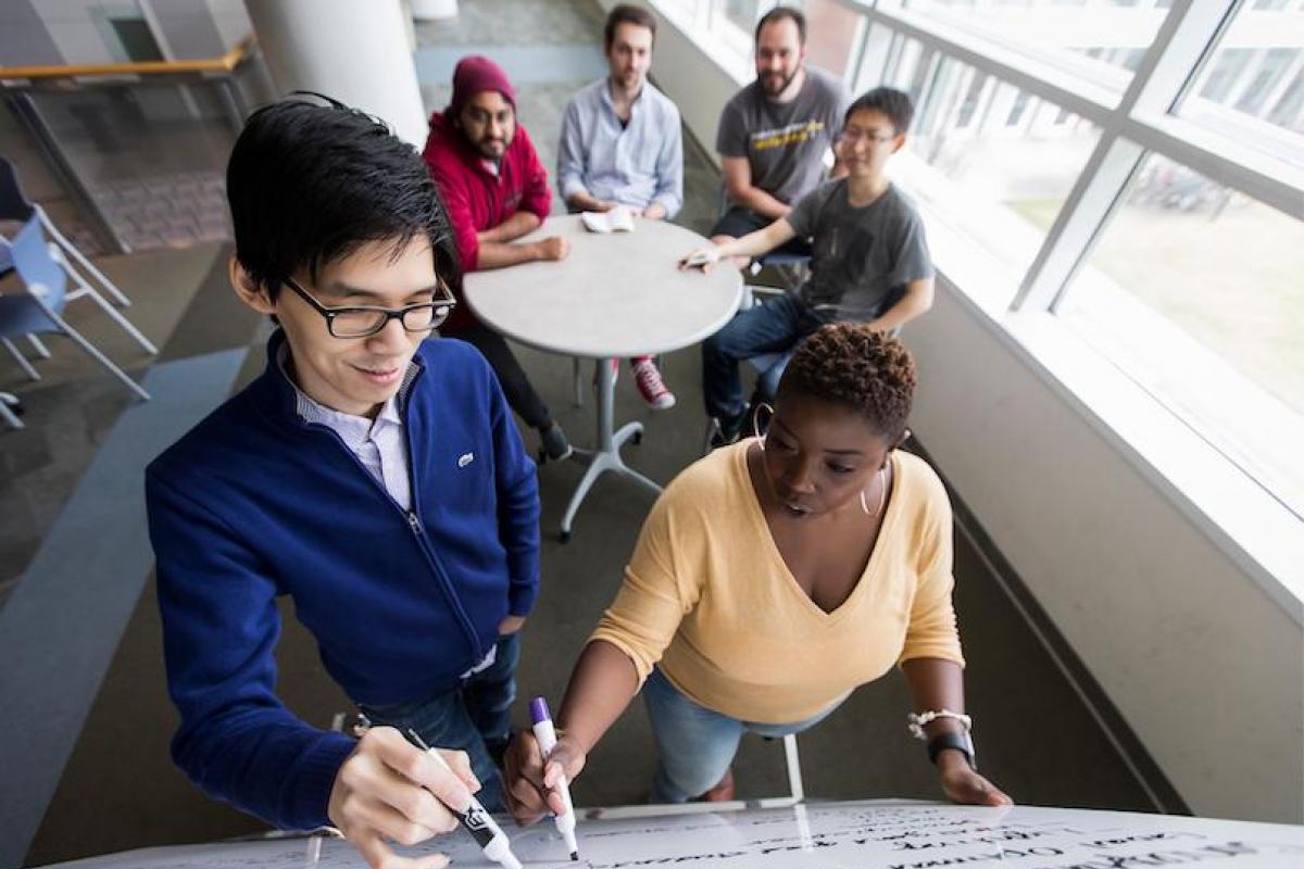 students writing on white board together