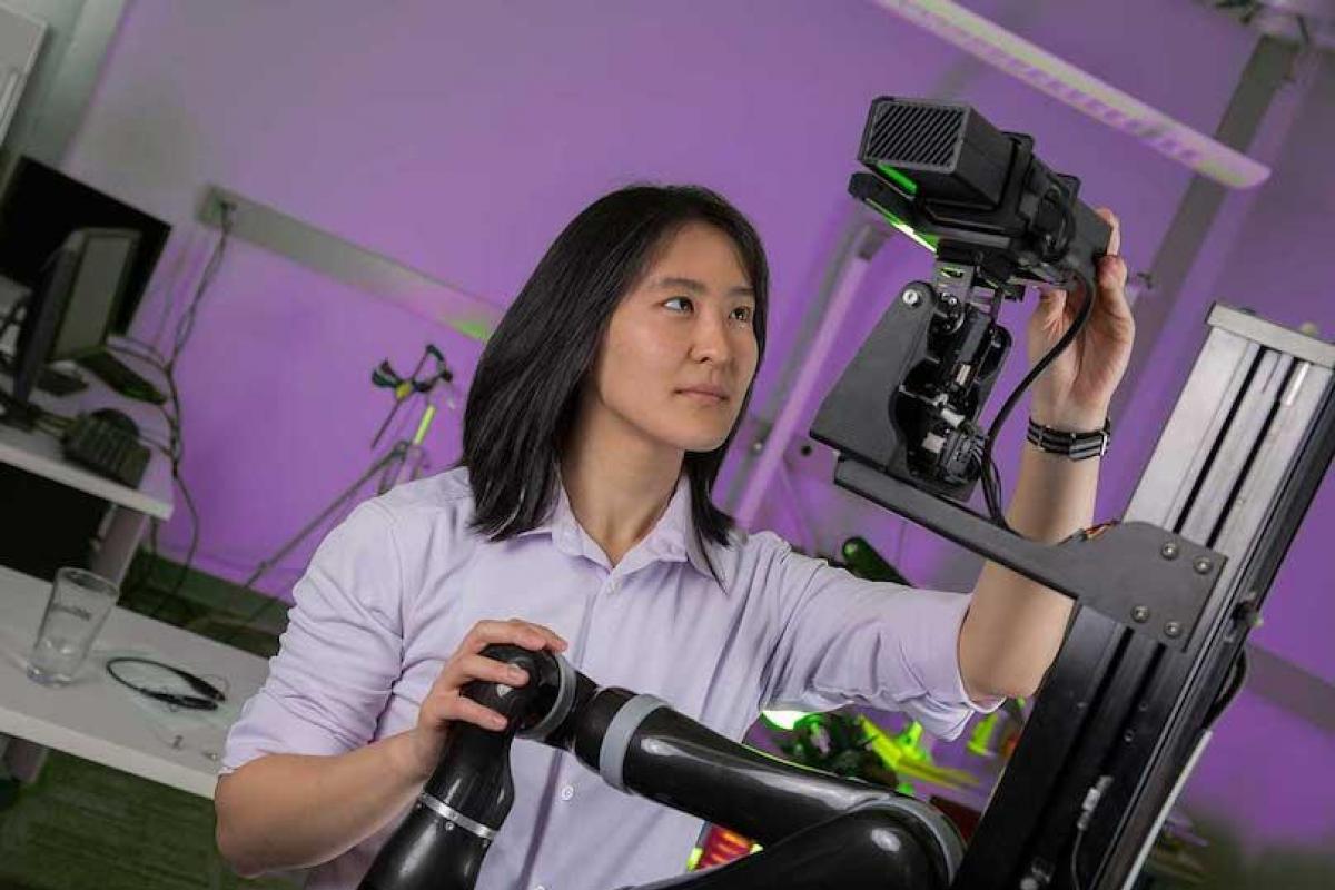 woman inspecting robot in lab